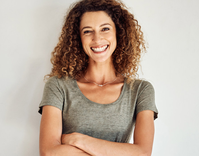 Portrait of smiling beatiful woman with curly hairstyle and arms